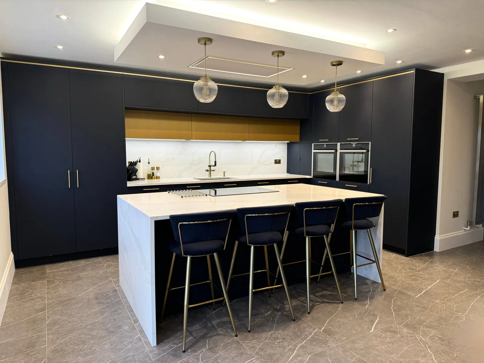 An Elegant Navy Blue Kitchen Featuring Quartz Worktops and a Waterfall Island